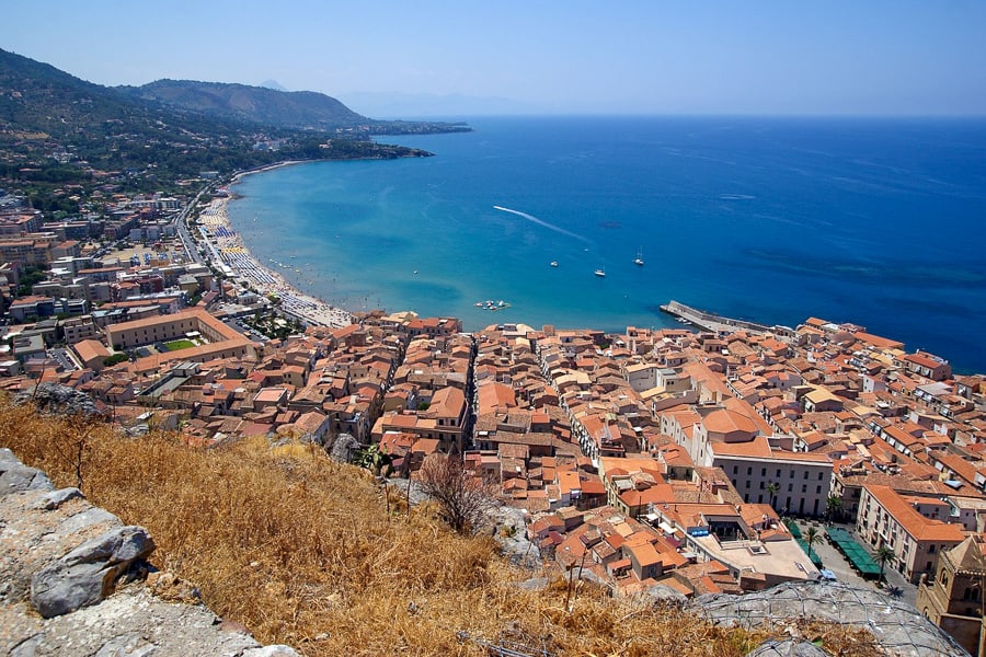 View over the terracotta rooftops and azure waters of Cefalù from La Rocca. 
