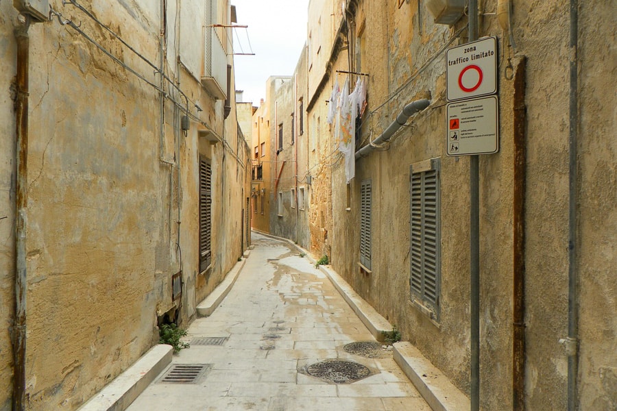 A narrow road with a Zona Traffico Limitato sign marking the entrance to an historical town centre, a regular site when driving Sicily.