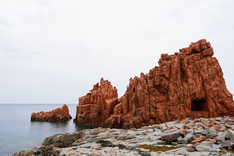 The red porphyry rocks of Red Rocks Beach are backed by a bright turquoise bay – but only when the sun behaves.
