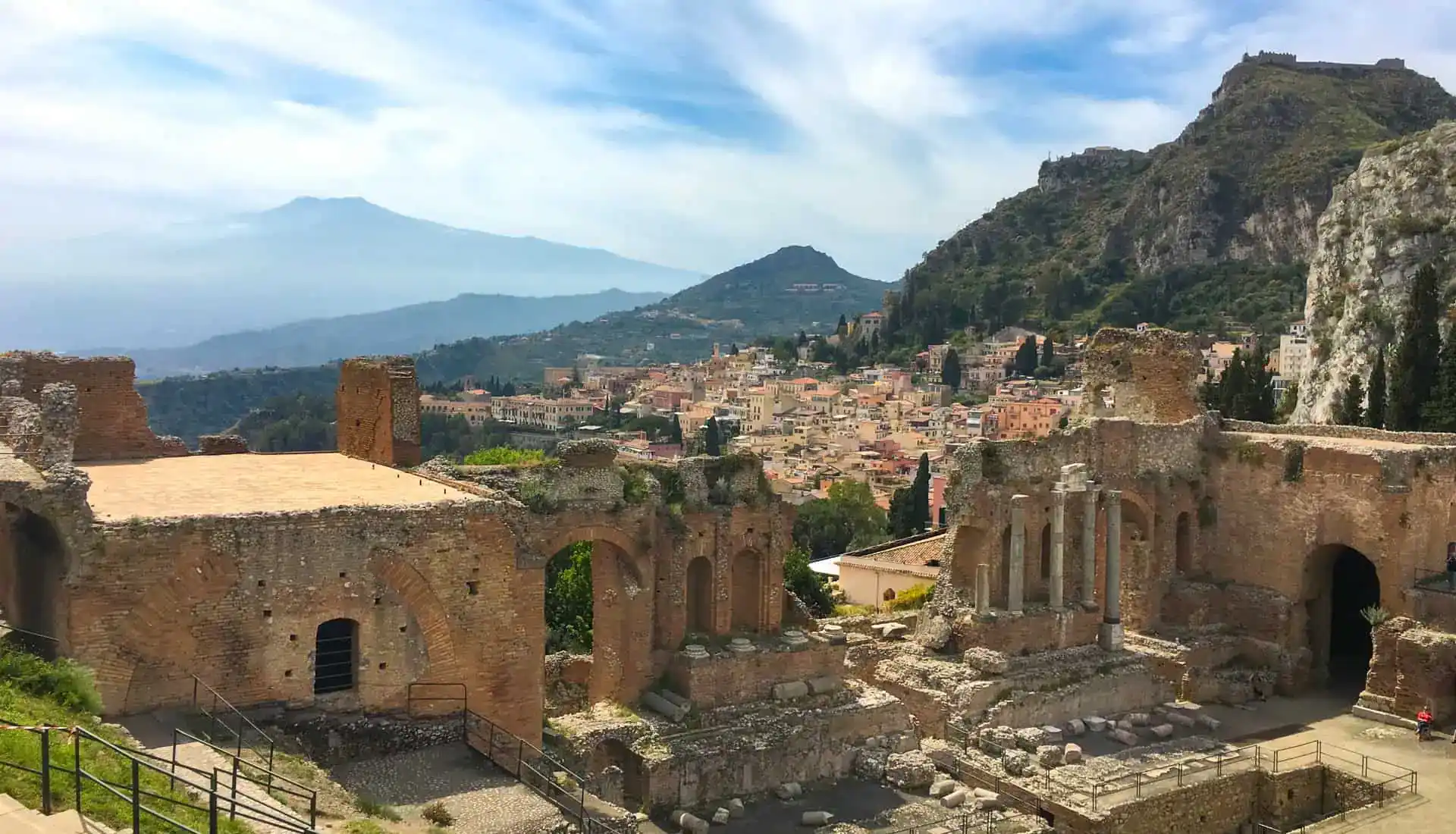 A Sicily road trip view over ancient ruins with Mount Etna in the background.