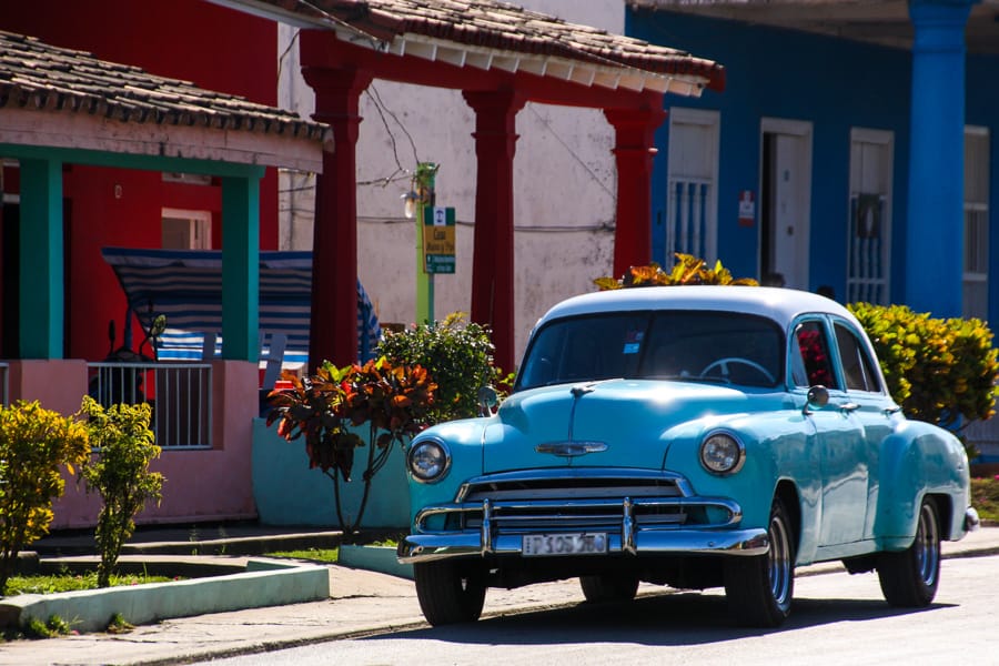 Blue vintage car outside colourful houses in Viñales, a regular site when travelling to Cuba.