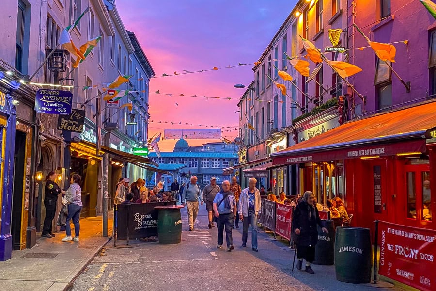 A colourful, pub lined street in Galway beckons at sunset during our Ireland road trip.