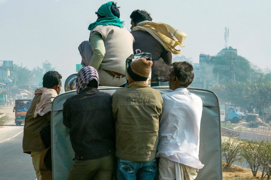 A group of people hanging on to the outside of a vehicle during our road trip in Rajasthan.