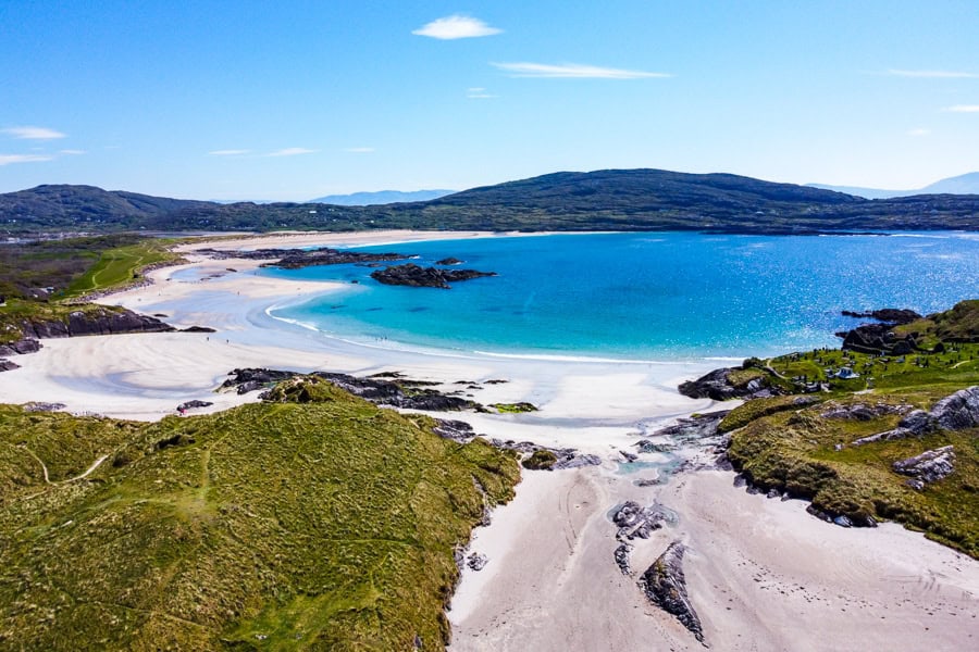 Views of the white sand and turquoise water of Derrynane Beach on a sunny day - a highlight of a southern Ireland road trip.