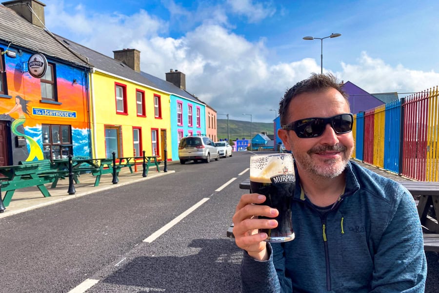 A customer enjoys a pint of Murphys on the colourful street outside O'Neill's Bar in Allihies.