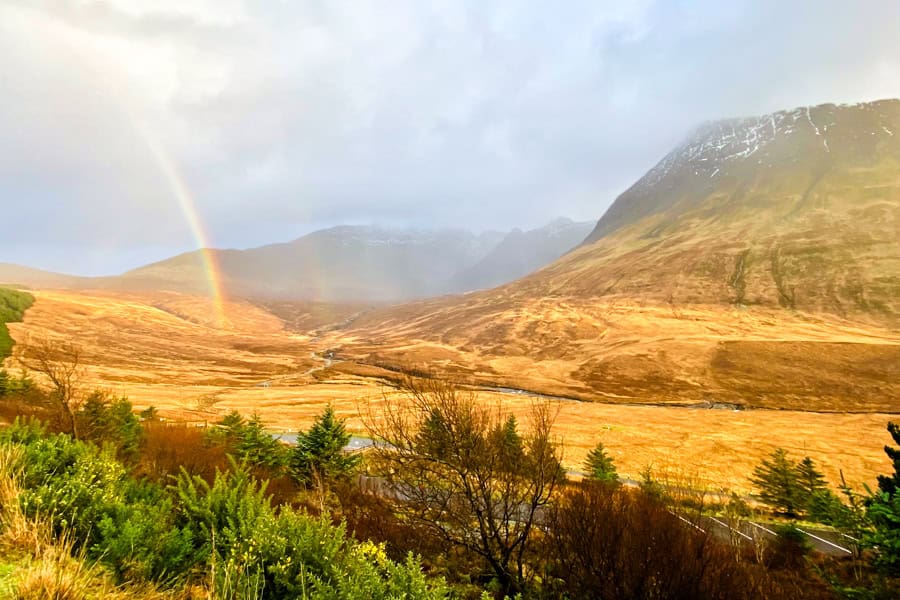 A rainbow over a golden valley at Fairy Pools, one of the top Isle of Skye attractions.