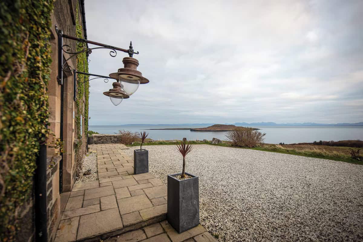 A stone building with a paved patio overlooking the sea.