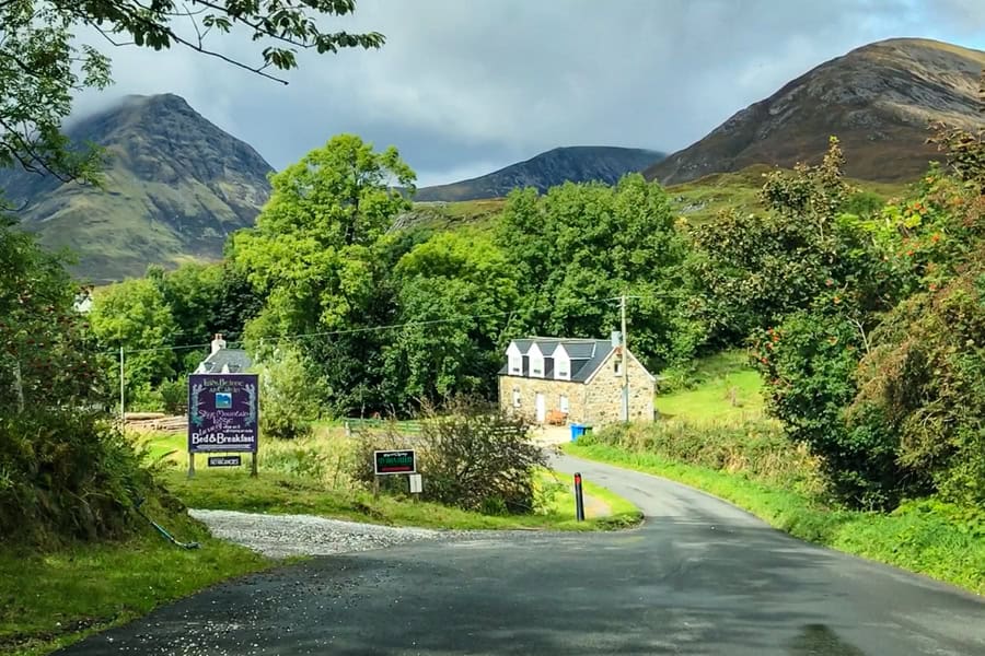 A road passing a house and an Isle of Skye B&B sign in foreground.