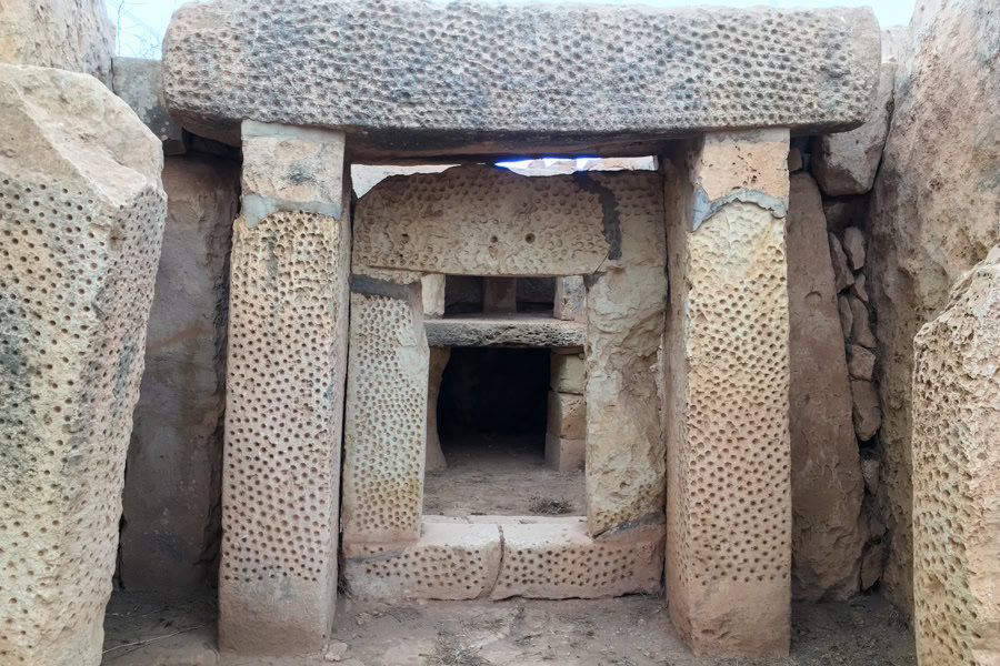 An ancient stone doorway decorated with pitted markings at Mnajdra, one of the top attractions in Malta.