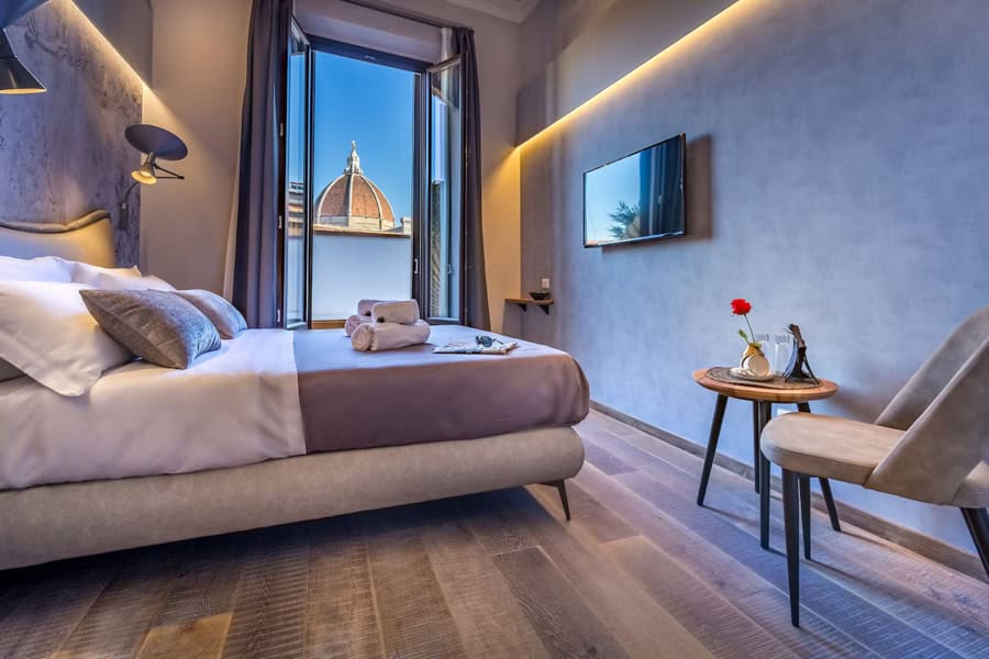 A hotel room with a bed and a window overlooking the Florence Duomo.