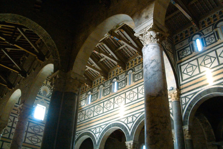 Interior of San Miniato al Monte with arches and a high beamed ceiling.
