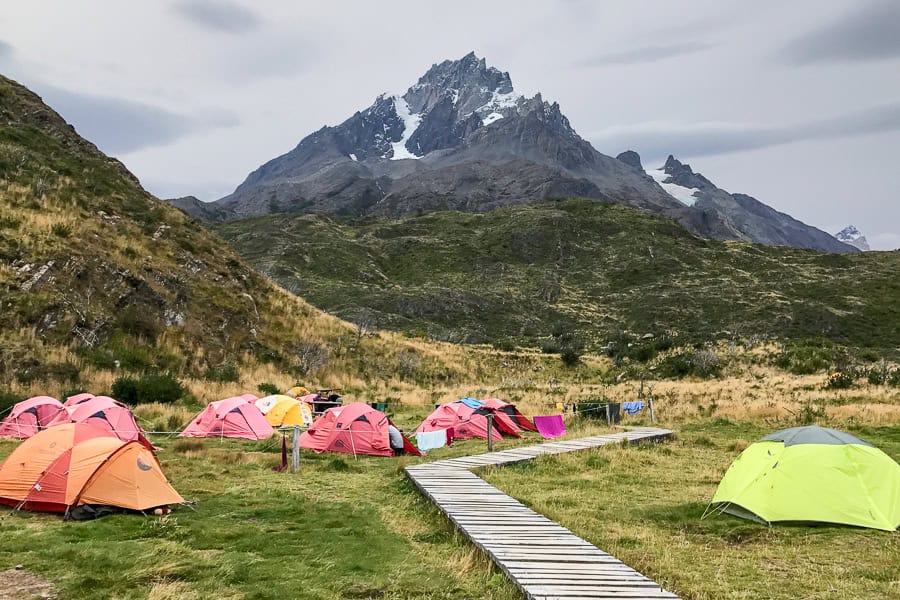 Red and yellow tents in a campground with a mountain in the background at Paine Grande in Torres del Paine.