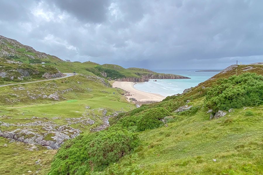 Ceannabeinne Beach backed by mossy hills and the Golden Eagle Zipline in case you want adrenaline on your nc500 road trip.