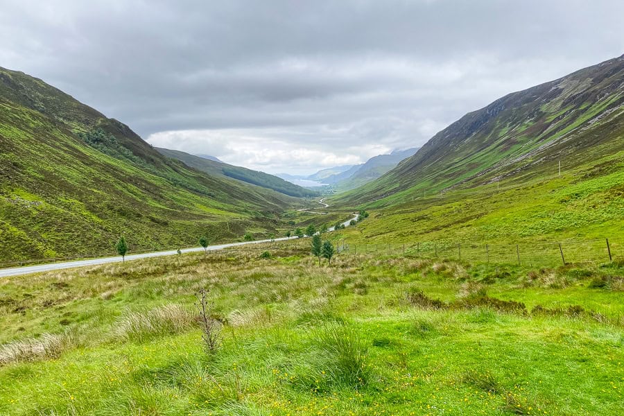 A road winds through the green hills of Glen Docherty towards Loch Maree on a Scotland road trip.