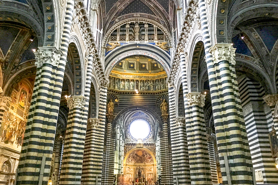 The striped marble interior of the Duomo di Siena is a Romanesque-Gothic masterpiece and highlight of a road trip in Italy.