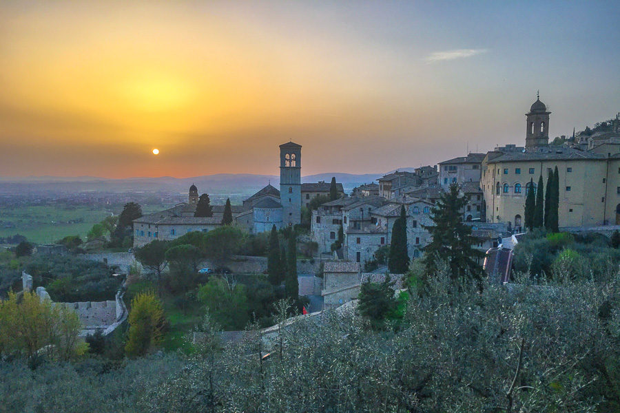 Sunset glows orange across the rooftops of Assisi, one of the most striking Italian hill towns we visited.