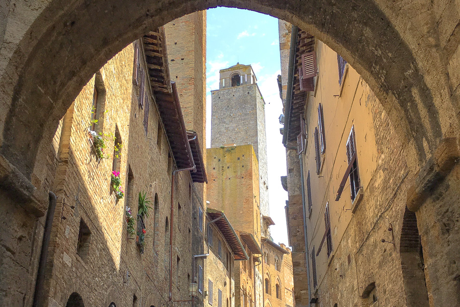 View through an ancient archway towards a medieval tower in San Gimignano, one of the prettiest hill towns of Italy.