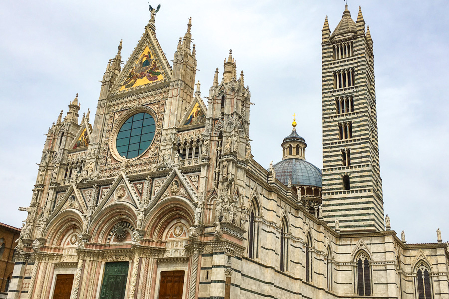 The black and white striped exterior of the Duomo di Siena during an Italy road trip.
