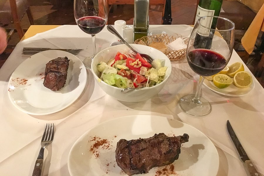 A table of steak, salad and red wine at Las Vacas Gordas restaurant – one of our gastronomic highlights of Santiago Chile.