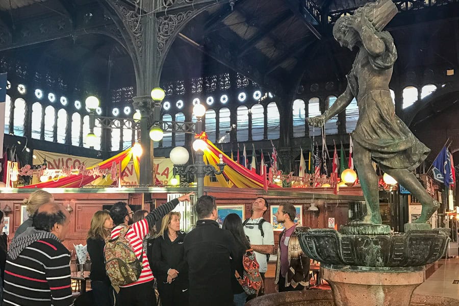 A tour group next to a statue at the Mercado Central on a walking tour, one of the more popular things to do in Santiago.