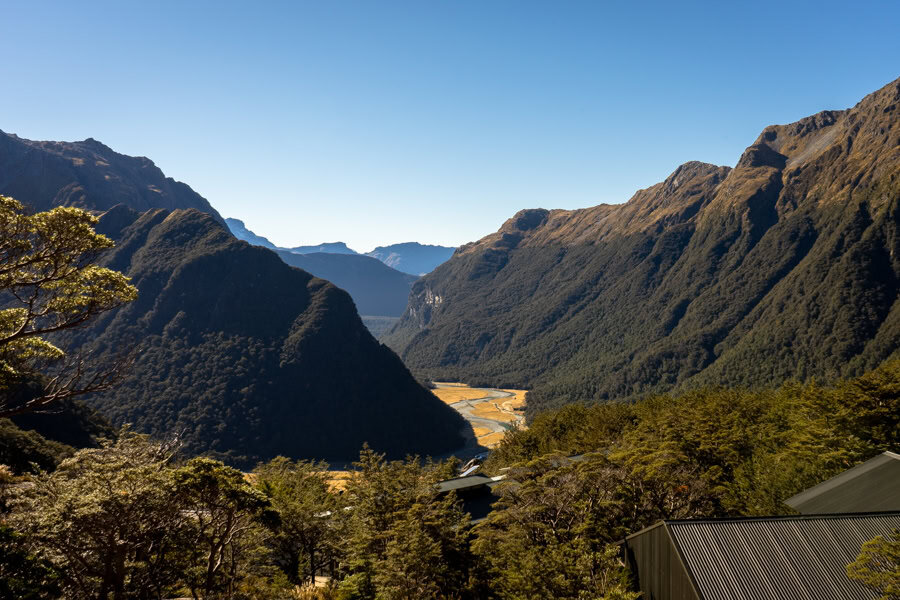 Looking out over hut roofs across mountains and a valley.