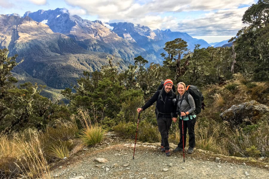 Two hikers with mountains behind hiking the Routeburn Track.