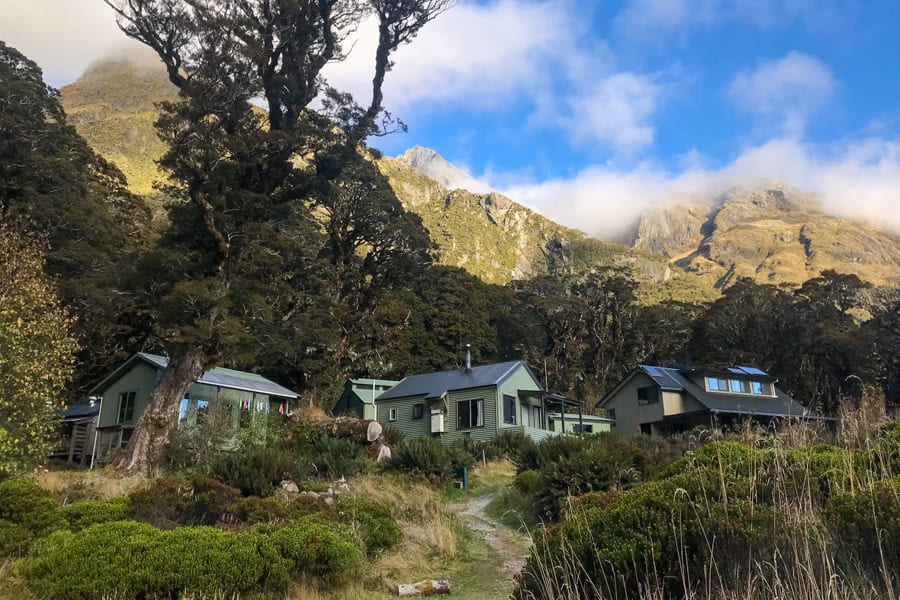 Routeburn Track huts backed by cloud-draped mountains.