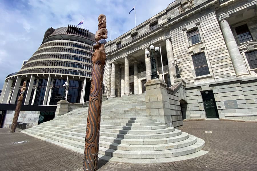 View of the beehive with 2 two carved pou whenua in the foreground – a tour here is a Wellington must do for political nerds.