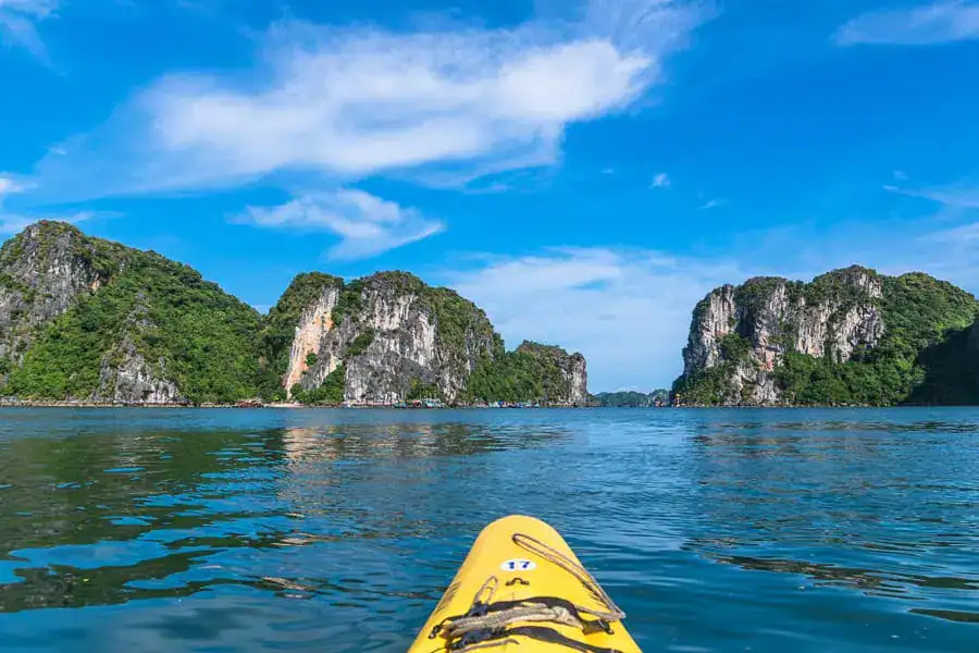 View from the front of a yellow kayak with limestone islands ahead on a Bai Tu Long Bay cruise.