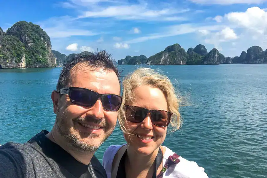 Two for the World on a Bai Tu Long Bay Cruise with Karst limestone pinnacles in the background.
