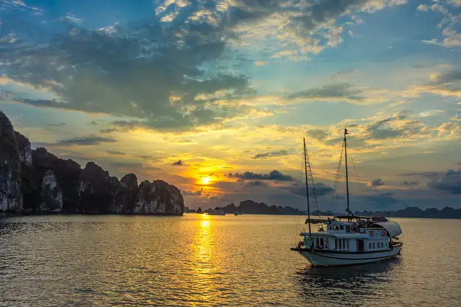 Burnt orange sunset over a quiet bay - whether you cruise halong bay or take a Bai Tu Long Bay cruise sunsets are memorable.