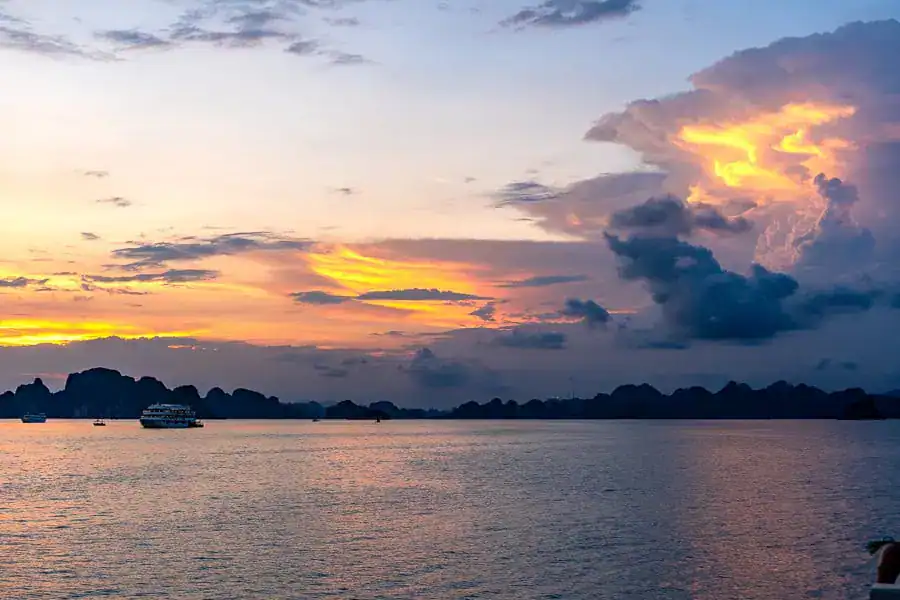 Storm clouds gather over limestone islands at sunset – a reminder that Halong Bay weather can be fickle.