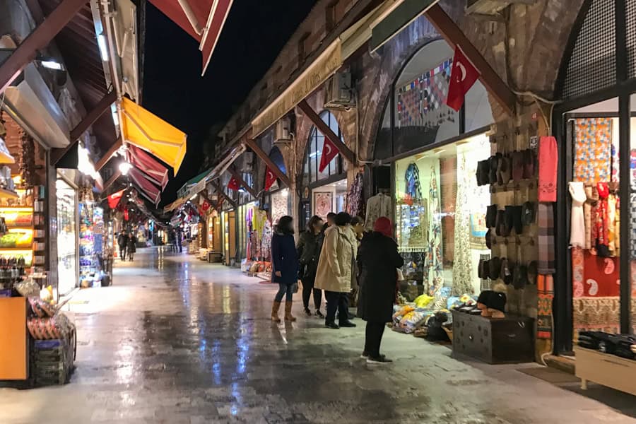 An arcade with shops and people browsing as they visit Istanbul.