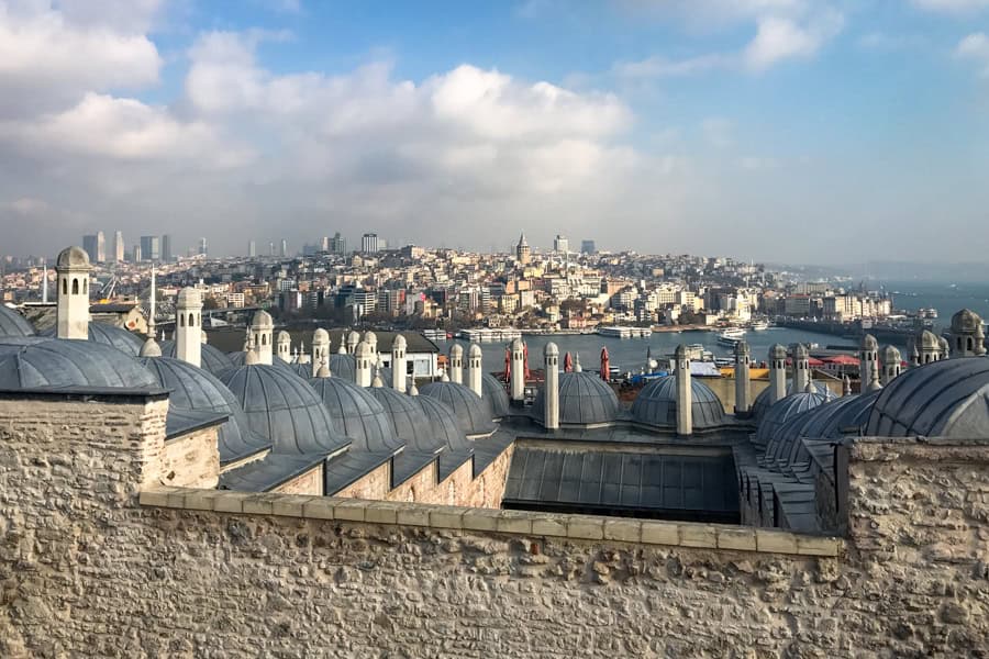 Towers and domes with a waterway and a city in the background.