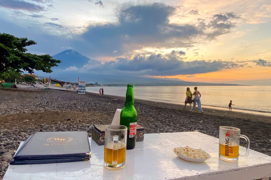 Two beers on a table at the beach at sunset – a simple moment that makes couple travel special.