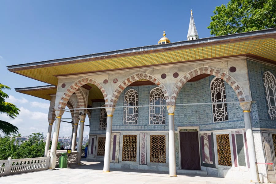 An ornate pavilion with blue tiles, arches and a yellow lintel, a Topkapı Palace highlight when visiting Istanbul.
