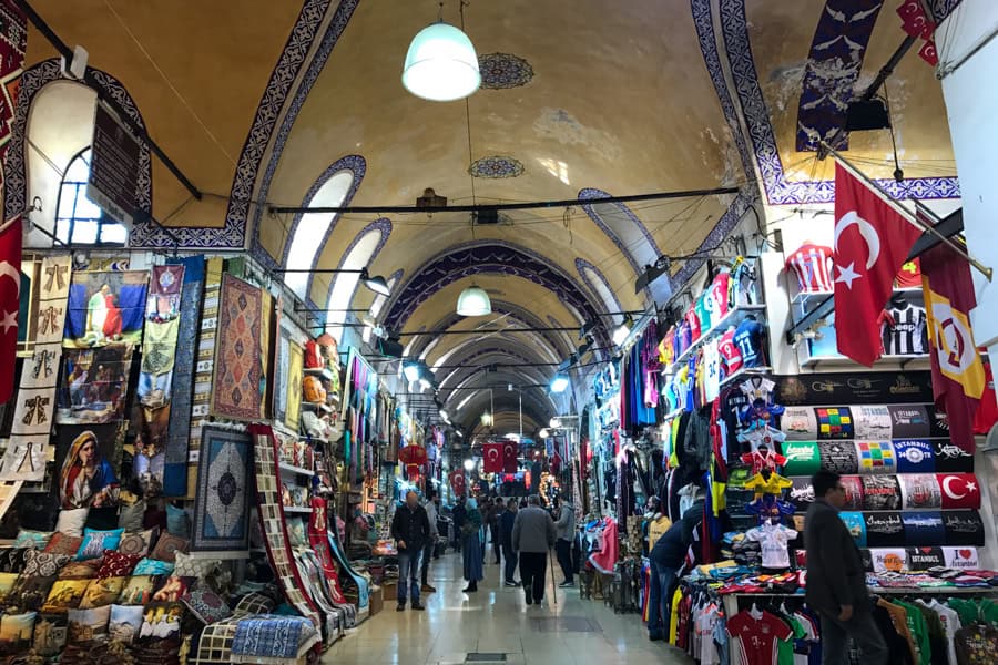 A large market arcade with painted vaulted ceiling and many people.