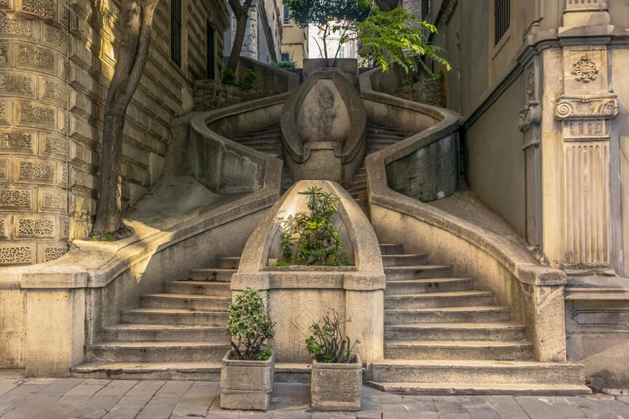Two sets of winding stone stairs lead up from a street between buildings.