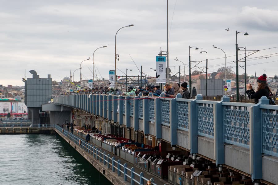 A bridge over water with people fishing off it.