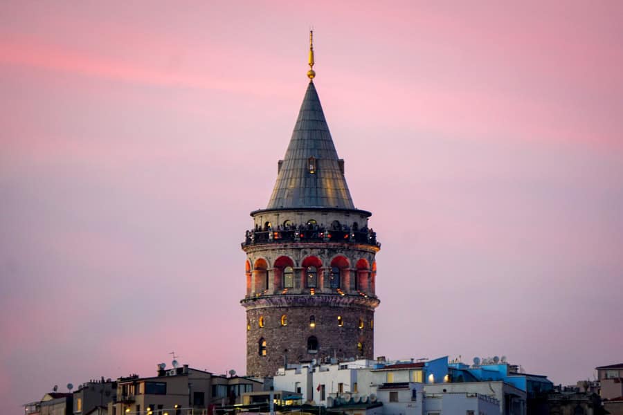 The upper levels and pointy roof of Galata Tower rises high above the surrounding buildings.