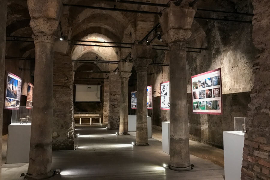 A room with columns, sculptures and pictures on the walls.