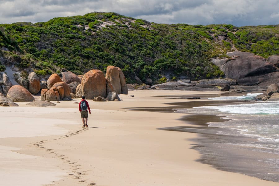 A person walking alone along a beach – taking time out while travelling as a couple.