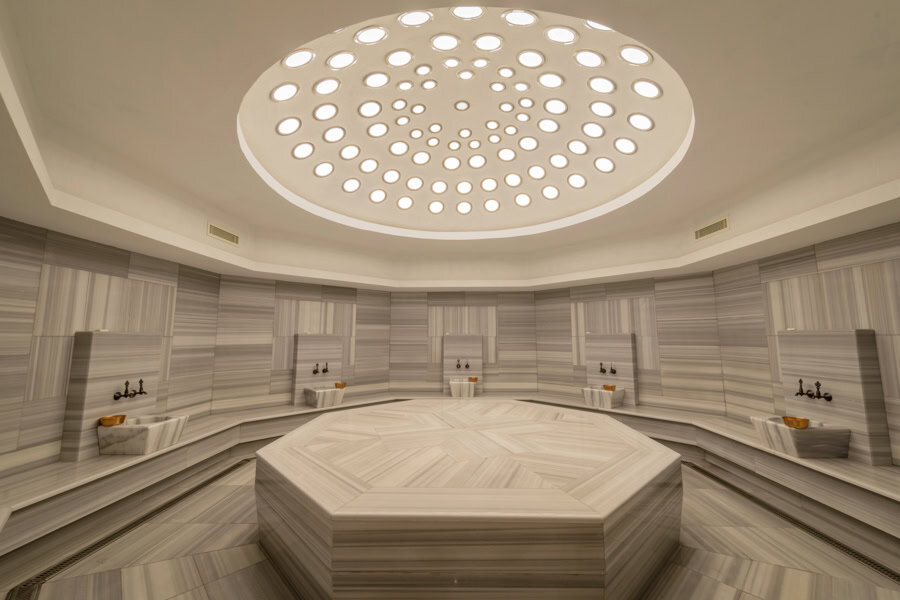 A marble tiled room with a hexagonal table in the middle.