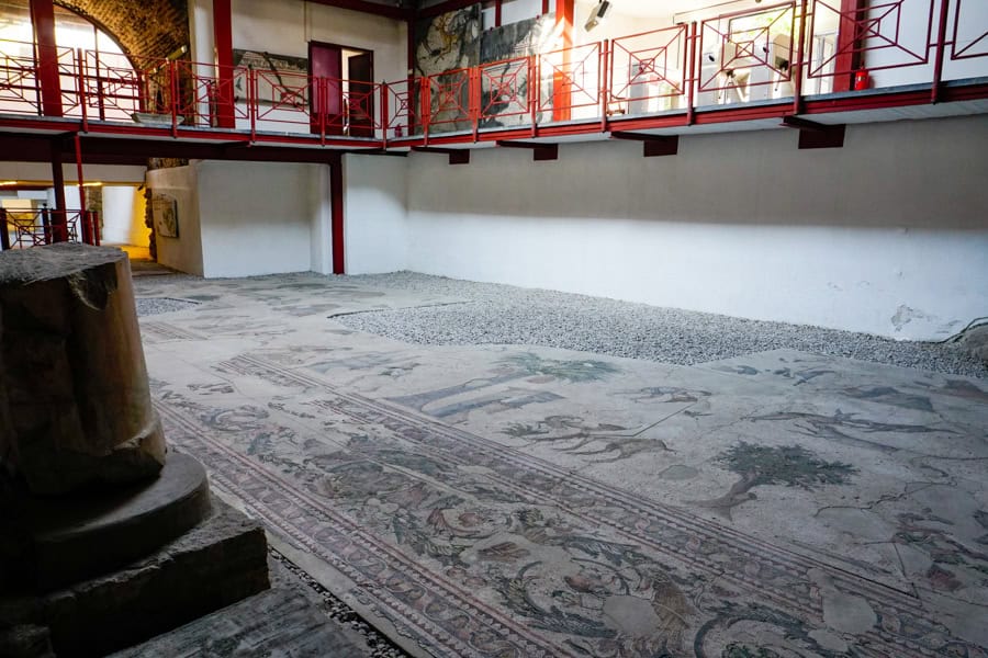 A room with a walkway above a restored mosaic floor.