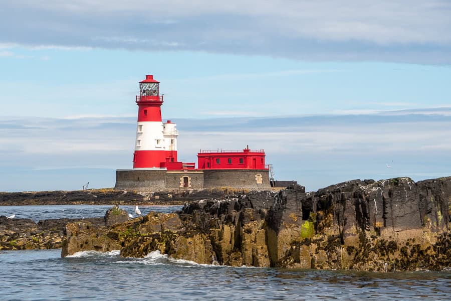 View of the distinctive red and white Longstone Lighthouse which still operates and can be seen on a Farne islands boat trip.