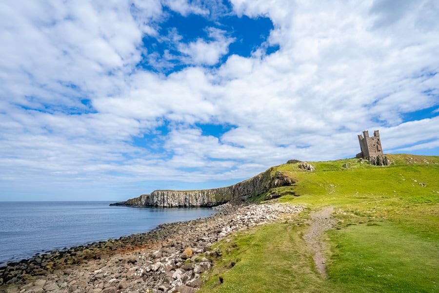 View of Dunstanburgh Castle ruins sitting above a rocky oceanside during our Northumberland 250 road trip.