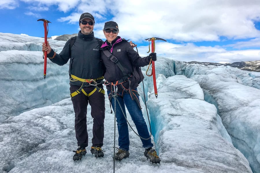A couple standing on the ice with warm clothes, crampons and ice axes during a Norway glacier hike.